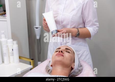 Professional cosmetologist prepares client's skin with special cream. Professional cosmetology and skin care. Stock Photo
