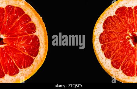 Fresh red grapefruit cut in half on black background. Negative space in the middle Stock Photo
