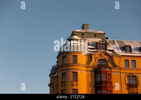 Yellow Scandinavian architecture historic building in central Stockholm, Sweden with snow on roof in early morning light against blue sky background Stock Photo