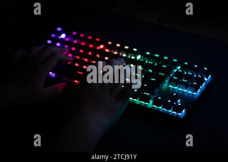 Neon computer keyboard with color backlight. Computer video games, hacking, technology, internet concept. Selected focus. A teenager plays a video gam Stock Photo