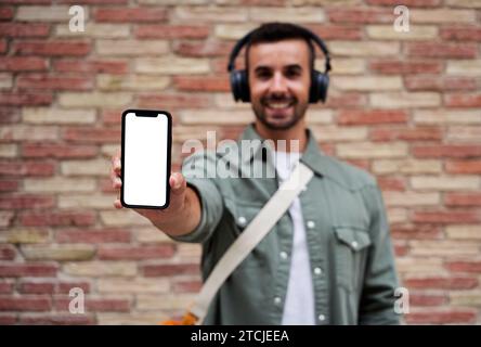 Young man showing phone to the camera with blank screen. Stock Photo