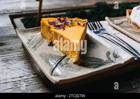 Pumpkin Pie Slice with rose petals on Decorative Ceramic Plate. A delicious slice of pumpkin pie topped with garnish, served on a botanical-themed Stock Photo