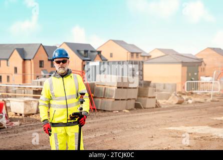 Surveyor builder site engineer with theodolite total station at construction site outdoors during surveying work Stock Photo