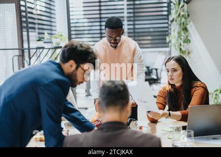 Multiracial professionals collaborate in a modern office, analyzing market data for business growth and increased productivity. Stock Photo