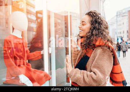 Smile happy   woman in a jacket and orange scarf walking outdoors, going window shopping, and looking for dress Stock Photo
