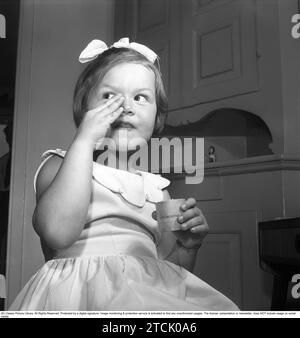 In the 1950s. A little girl is putting on makeup, applying coldcreme on her face, a product used to protect the skin from becoming dry and red. 1956. Kristoffersson ref BS95-1 Stock Photo