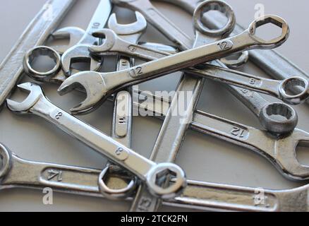 Laid out in disarray on top of each other chrome plated wrenches of different sizes Stock Photo