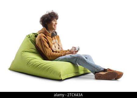 Guy sitting on a green bean bag armchair and playing a game with joystick isolated on white background Stock Photo