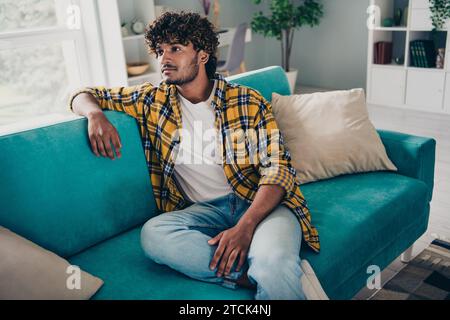 Portrait of minded pensive person sit cozy sofa contemplate ponder spend free time day apartment inside Stock Photo