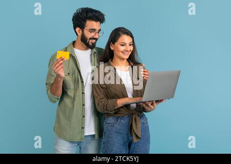 Cheerful millennial indian couple using laptop and credit card Stock Photo