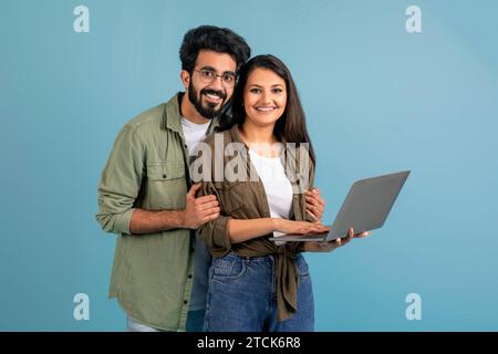 Happy millennial indian couple using laptop together, choosing purchase Stock Photo