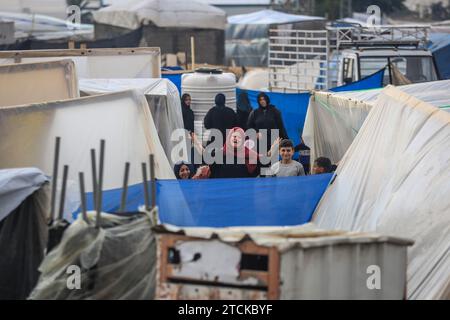 Rafah, Palestinian Territories. 13th Dec, 2023. Palestinians walk near makeshift tents at camp for displaced people. Credit: Mohammed Talatene/dpa/Alamy Live News Stock Photo