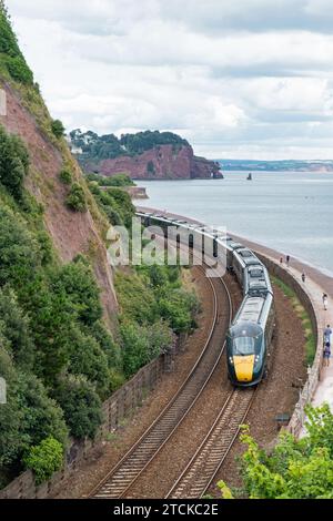 Devon, England – July 21, 2023: A Great Western Railway passenger train from London Paddington on the scenic route along the coast near Teignmouth Stock Photo