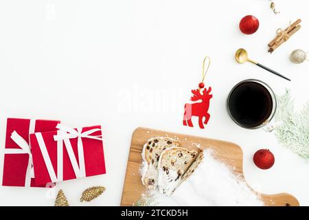 Christmas table with tasty stollen cake, coffee cup, tree toys and gift boxes on white. Flat lay, top view. Stock Photo