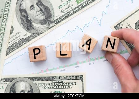 Business concept. On a brown surface are dollars, a calculator and wooden cubes with the inscription - PLAN Stock Photo