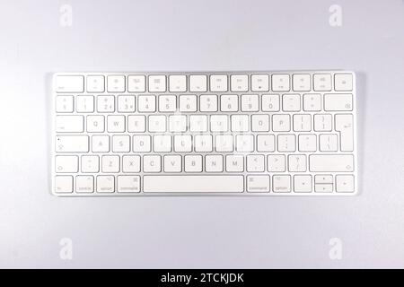 Top view of a compact wireless white Apple keyboard placed on a light gray surface. Stock Photo