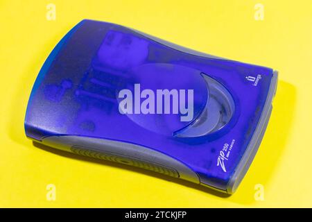 Close-up of a blue Iomega Zip 250 external floppy drive on a bright yellow background. Stock Photo
