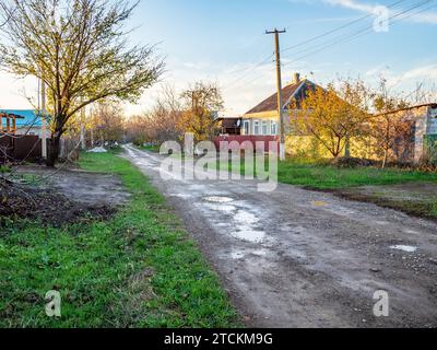 wet dirty street in village after rain at autumn sunset Stock Photo