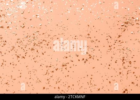 Festive background with shiny confetti. Holiday concept. Color of the Year 2024 Peach Fuzz. Stock Photo