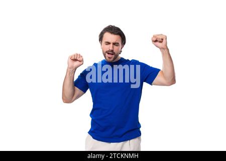 emotional young brunette man with a beard dressed in a blue t-shirt on a white background Stock Photo