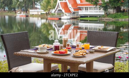 Outdoor breakfast setup at lakeside resort with reflection of nature. Travel and leisure. Stock Photo