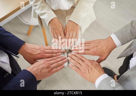 Three business partners put their hands together as symbol of unity, motivation and cooperation. Stock Photo