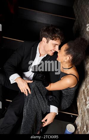 cheerful multicultural couple having great time on date at cinema and smiling at each other lovingly Stock Photo