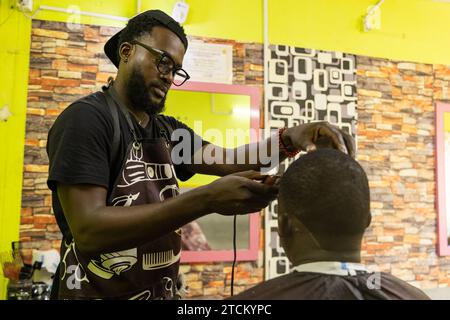 A barber is focused on cutting his client's hair in his salon. Stock Photo