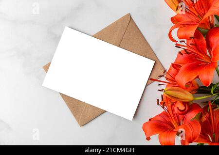 Blank greeting card with orange lily flowers on white background. Wedding invitation. Mock up. Flat lay Stock Photo