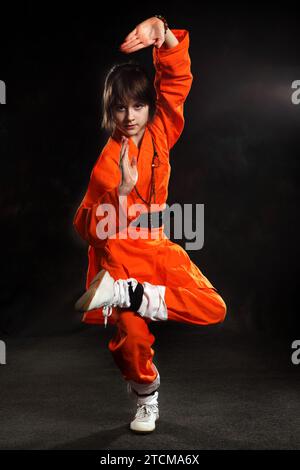 Wushu Girl dressed in orange make exercise of Shaolin taolu Stock Photo