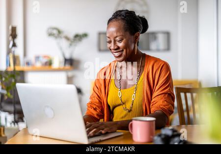Smiling woman working on laptop at home Stock Photo