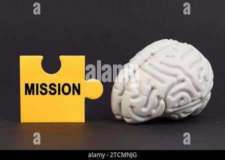 On a black surface there is a brain and a yellow puzzle with the inscription - Mission. Education and business concept. Stock Photo