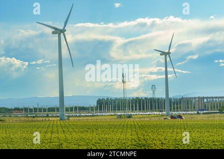 Wind generators in the field, next to the car park, in the background of the mountain. Stock Photo