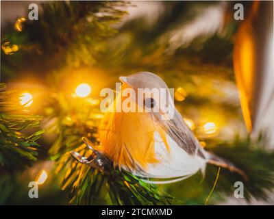 A vibrant red Christmas ornament hanging from a lush tree of pine branches Stock Photo