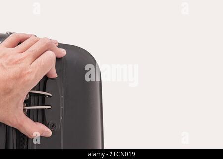 Hand opens lock on black plastic suitcase isolated on white background Stock Photo