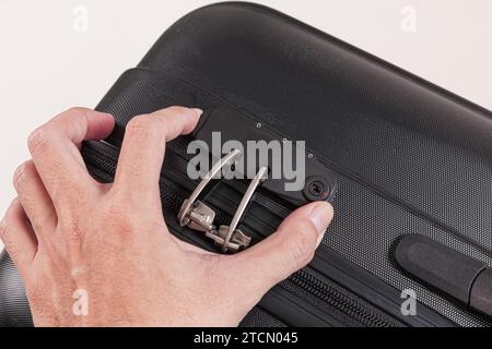 Hand opens lock on black plastic suitcase isolated on white background Stock Photo