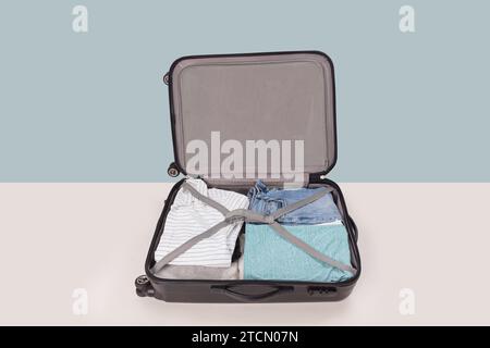 Open suitcase packed for trip isolated on light blue background Stock Photo