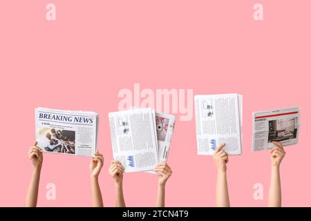 Female hands with different newspapers on pink background Stock Photo