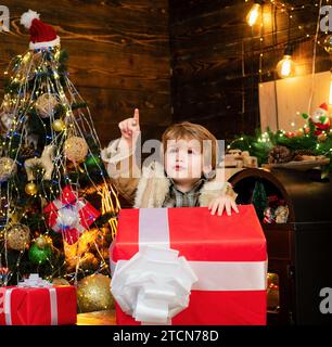 Happy child with Christmas gift. Happy kid having fun with big gift box. Christmas decorations. Wish you merry Christmas. Stock Photo