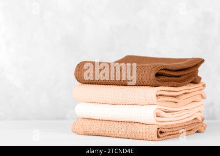 Stack of colorful cotton kitchen towels toned with color of the year 2024 Peach Fuzz Stock Photo