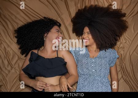 Half-closed portrait of two women lying down looking at each other. Solid friendship concept. Stock Photo