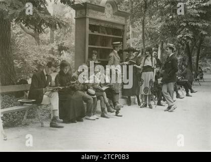 Madrid, August 1921. An image of the library established in the Retiro. Children and adults read on the benches arranged around the bookshelf full of books. In it we can read: 'These books, which belong to everyone, are entrusted to the custody of everyone.'. Credit: Album / Archivo ABC / Larregla Stock Photo