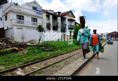 A Malagasy woman carrying a heavy bag on her head along the road in central Madagascar. Stock Photo