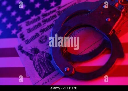 US Tax refund check and handcuffs on flag of United States of America close up. Record criminal investigation Stock Photo
