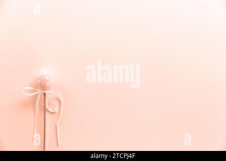 Colorful easter egg on stick. Easter minimal concept, flat lay. Colors of year 2024 - Peach Fuzz Stock Photo