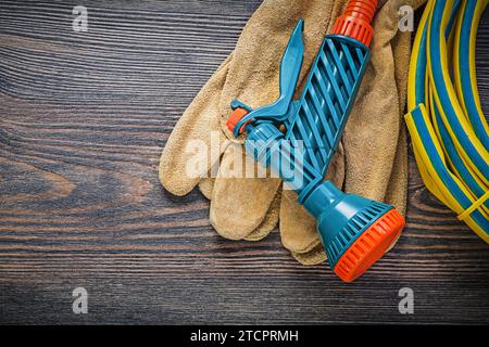 Hand spraying garden rubber hose protective gloves on wooden board gardening concept Stock Photo