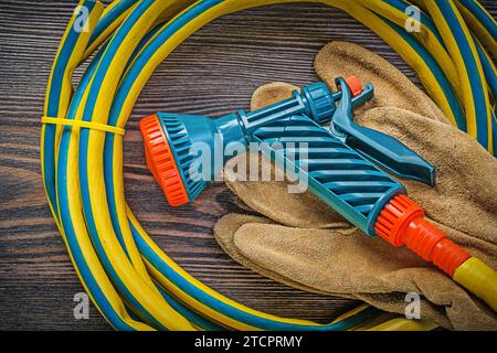 Hand spraying garden rubber hose safety gloves on wooden board agriculture concept Stock Photo