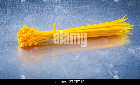 Yellow self-locking plastic cable ties on a metallic background Design concept Stock Photo