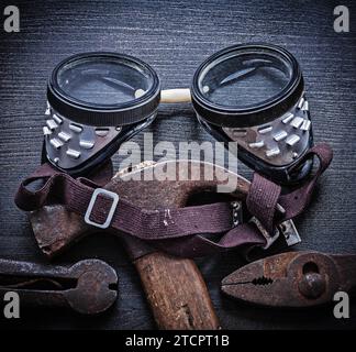 Safety goggles Hammer pliers on old wooden board Stock Photo