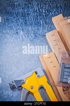 Yellow construction stapler metal staples wooden boards on metallic background Stock Photo